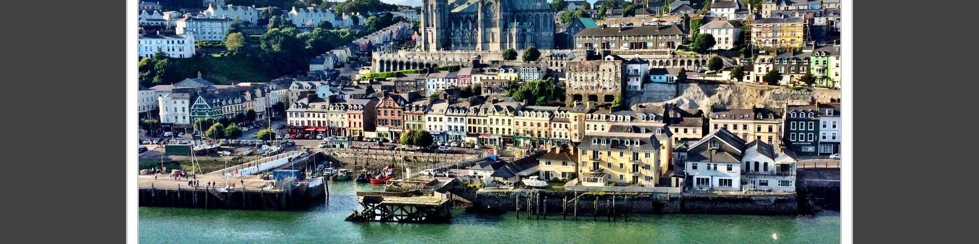 A coastal cityscape with a prominent cathedral and a harbor.