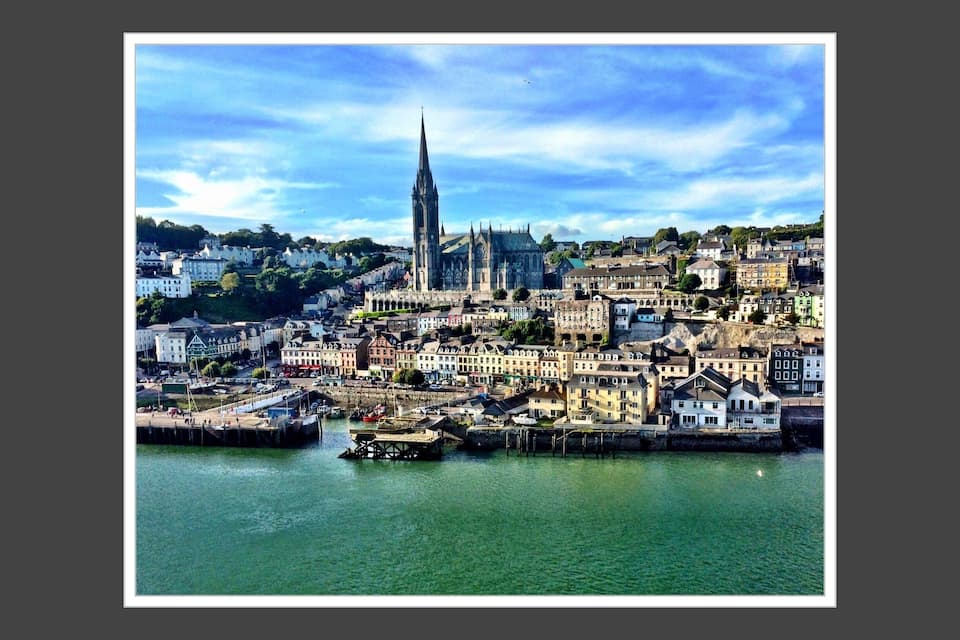 A coastal cityscape with a prominent cathedral and a harbor.