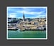 A coastal cityscape with a prominent cathedral and a harbor.