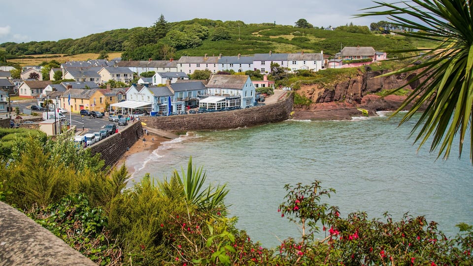 A coastal town with colorful houses, a rocky shoreline, and a beach.