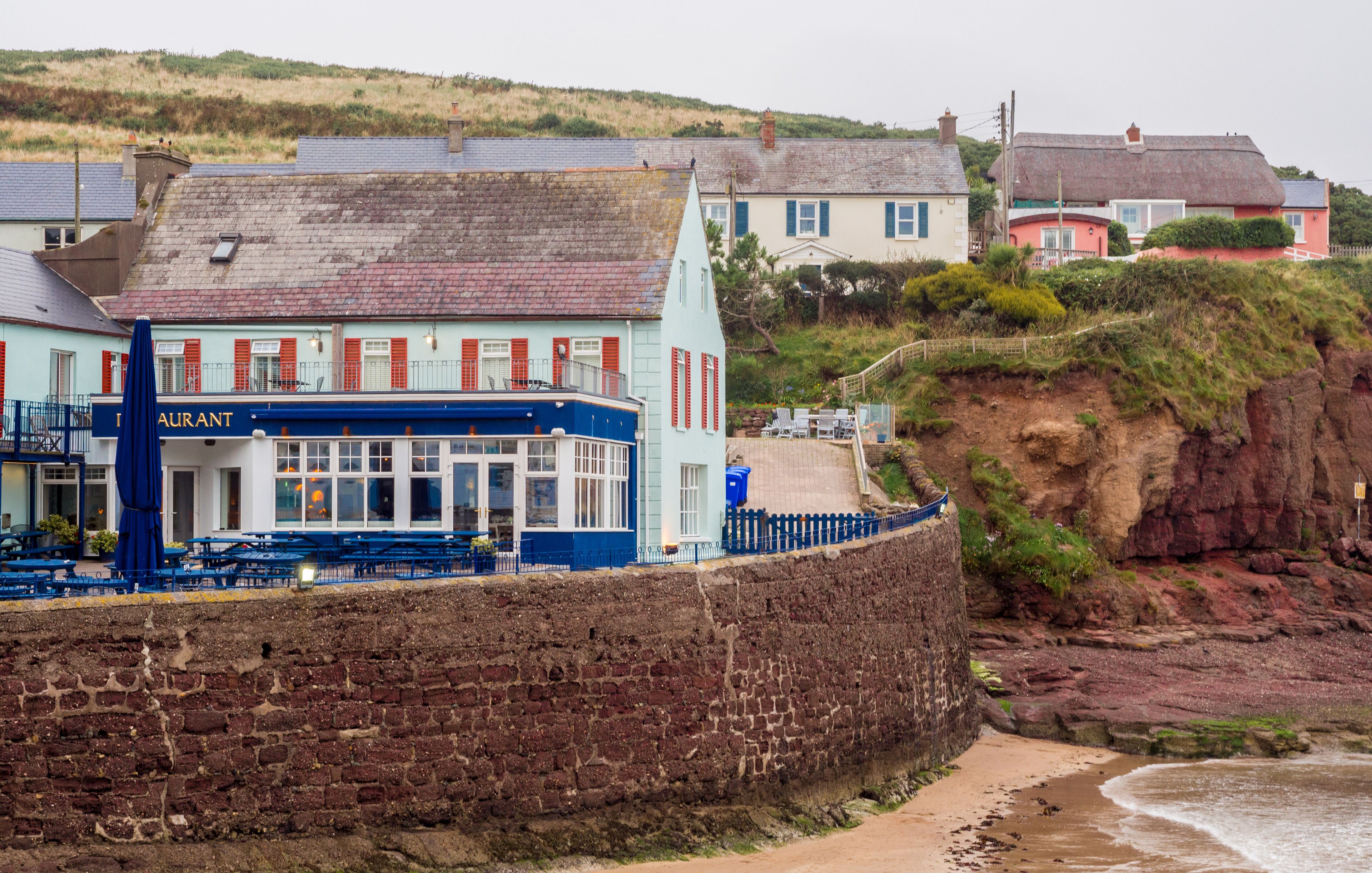 A coastal town with a restaurant named 'Restaurant' and a stone wall along the beach.