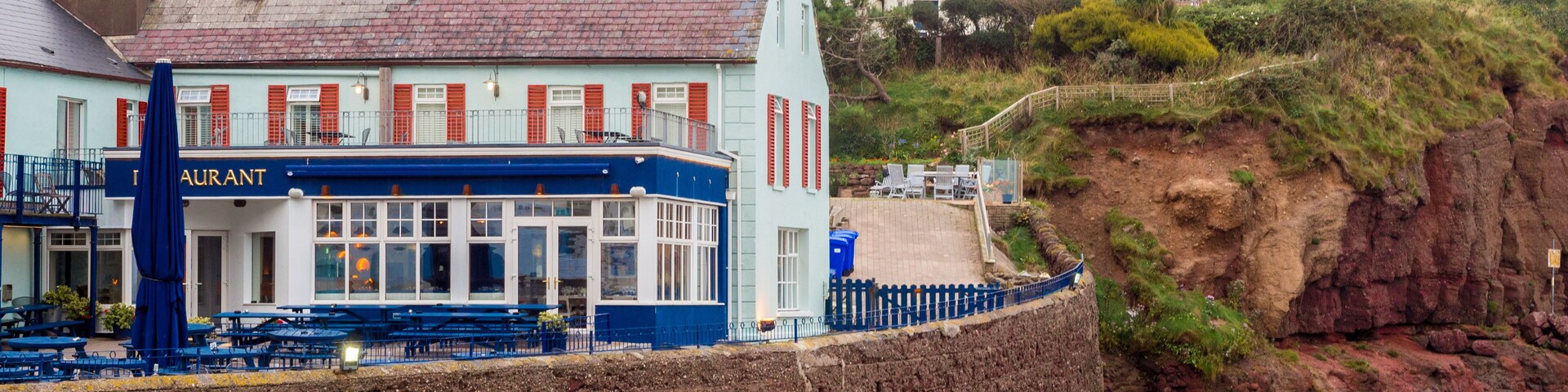A coastal town with a restaurant named 'Restaurant' and a stone wall along the beach.