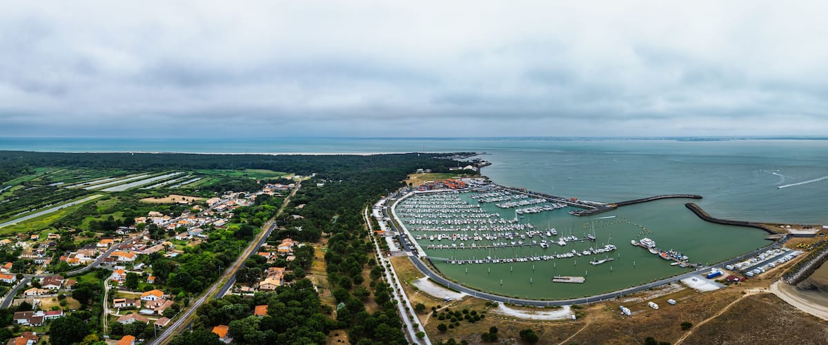 An aerial view of a coastal town with a marina, residential area, and a large body of water.