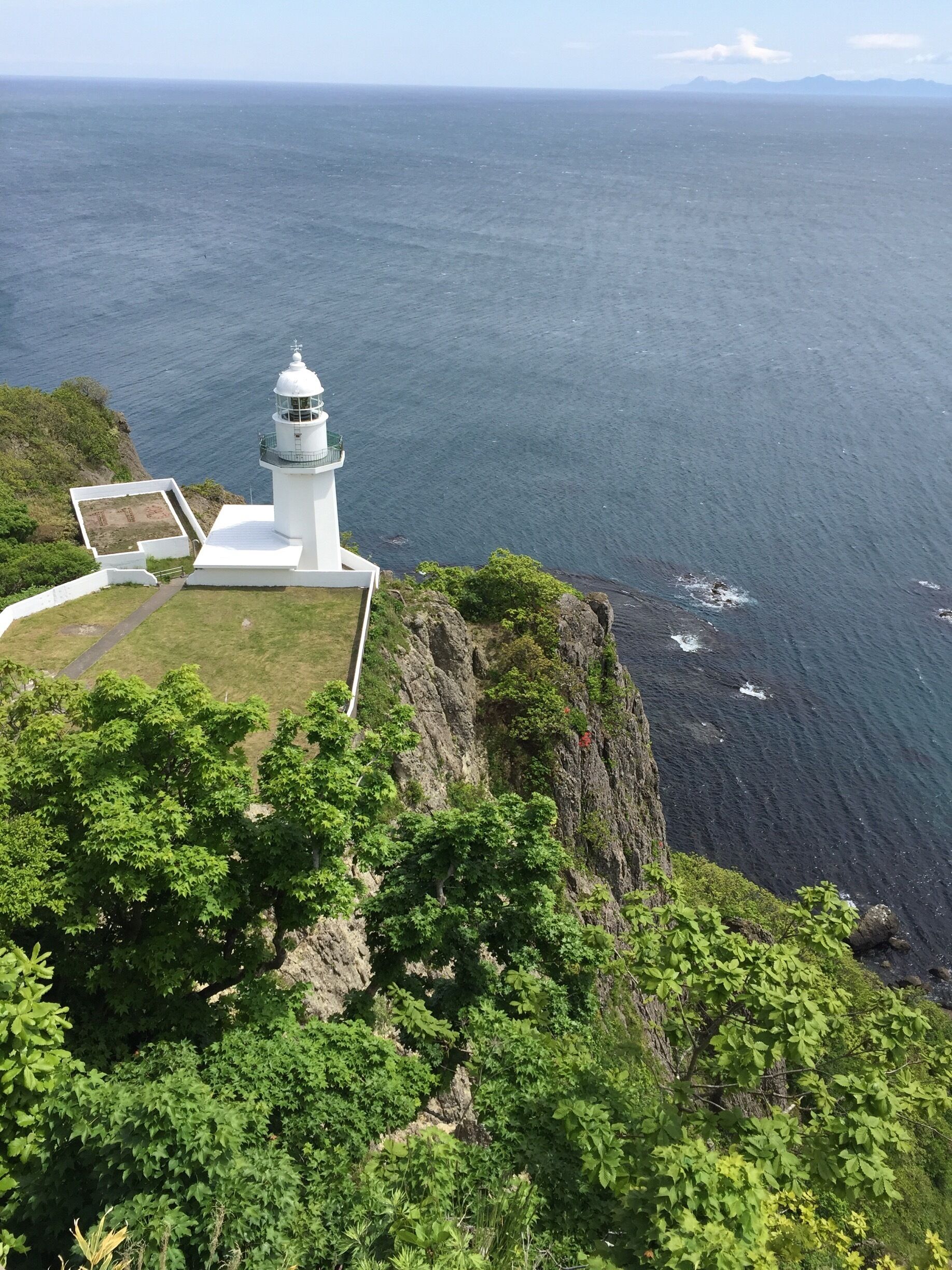 A white lighthouse on a cliff overlooking the ocean.
