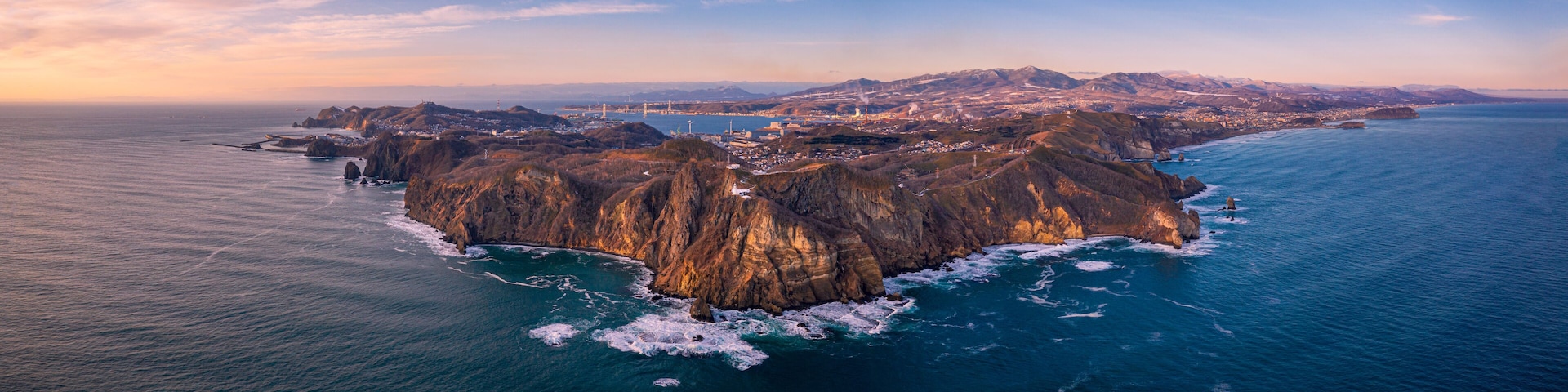 A rugged island with steep cliffs and a small town at its base.