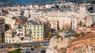 A cityscape with historic buildings, a prominent clock tower, and a mountainous backdrop.
