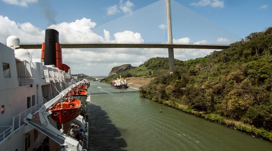 Un río con un puente, un barco y un paisaje montañoso.