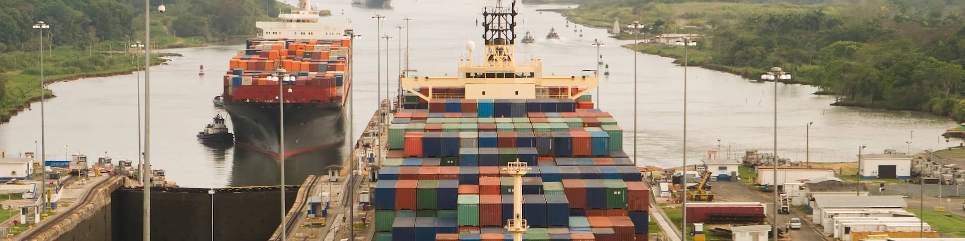 A large cargo ship docked at a port with multiple containers stacked on its deck.