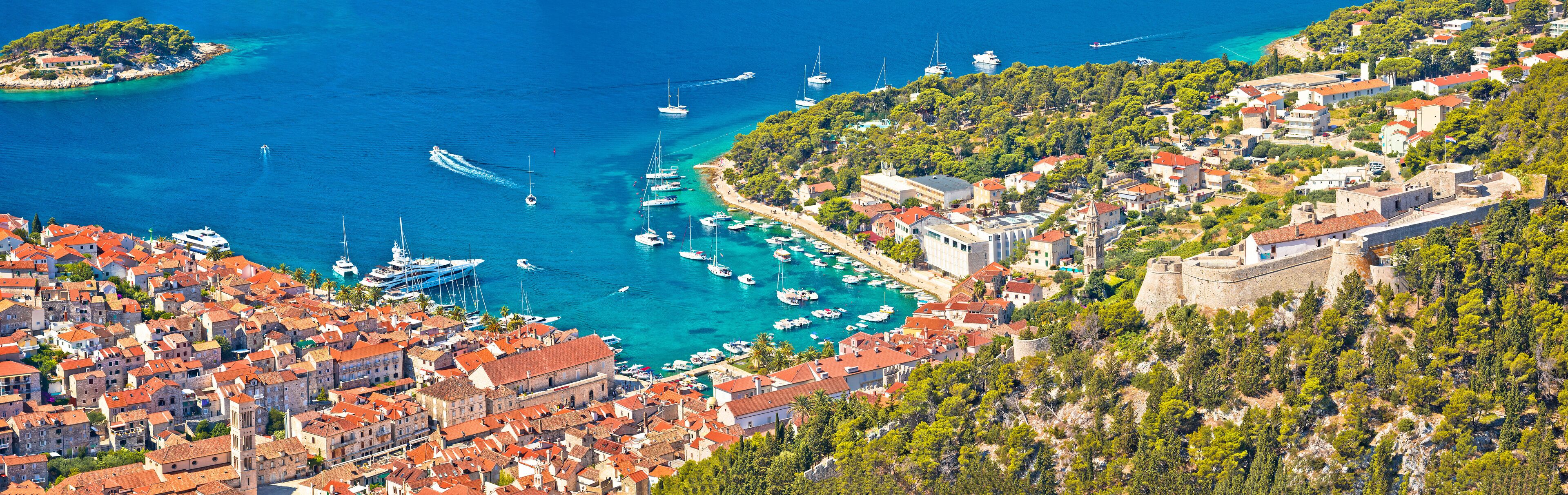 A coastal town with a marina, historic buildings, and a castle on a hill.