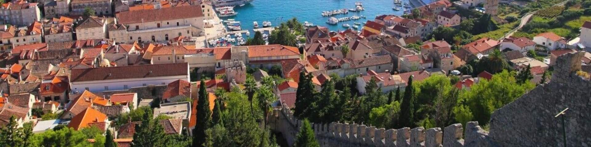 A coastal town with historic buildings, a harbor with boats, and a prominent castle wall.