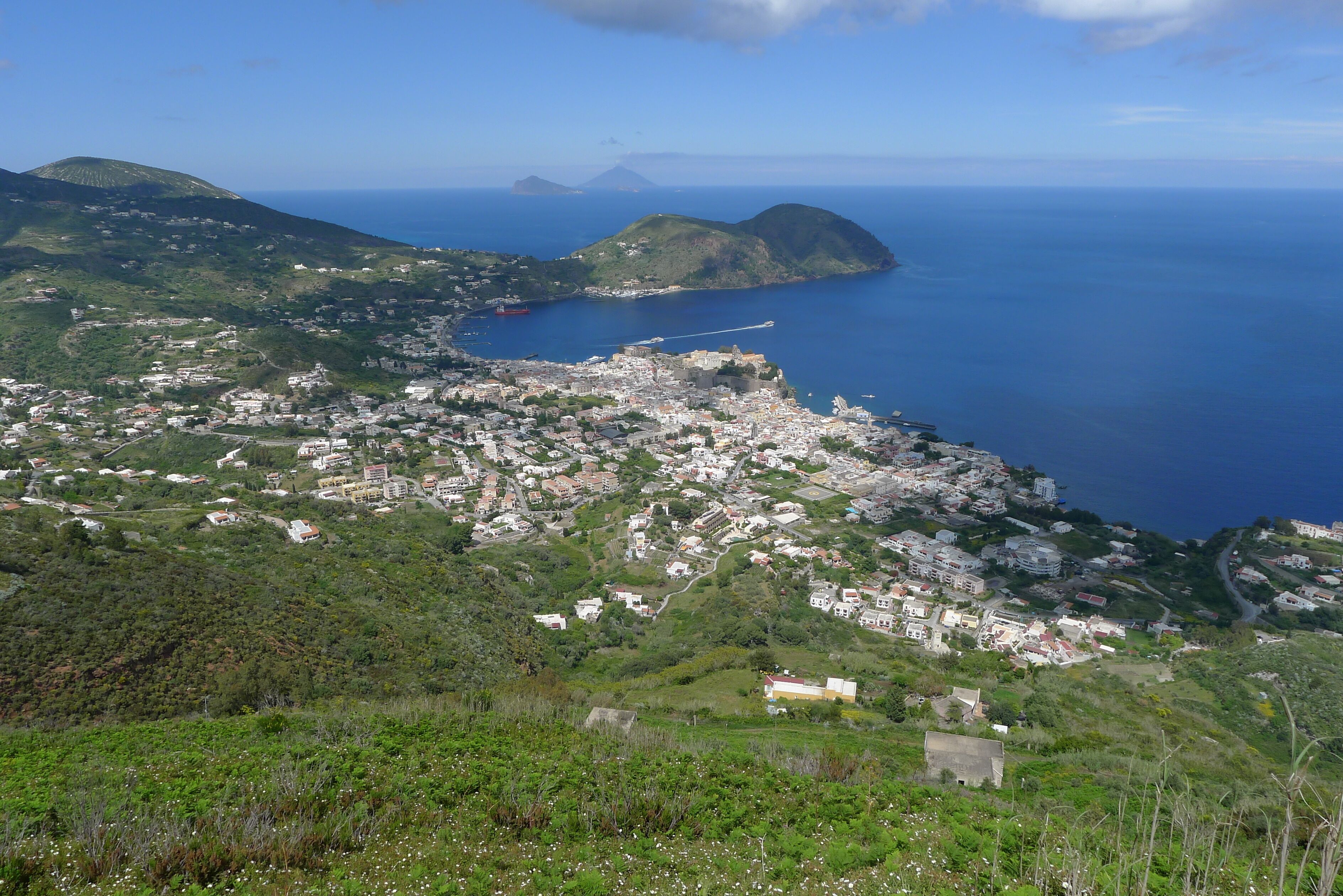A coastal town with a harbor, surrounded by hills and mountains.