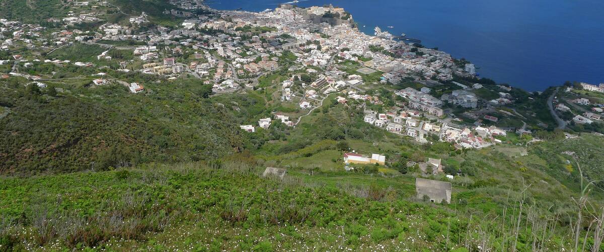 A coastal town with a harbor, surrounded by hills and mountains.