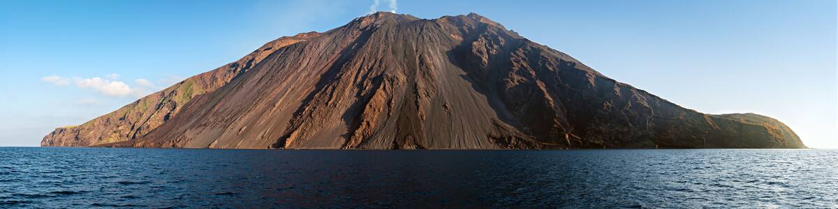 The stromboli vulcano erupting on the "Sciara del Fuoco" north west side, day shot, blue sky background, panoramic shot, eolians islands, sicily, italy
