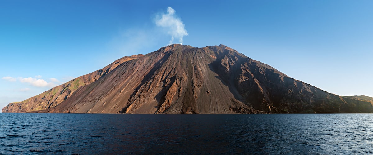 The stromboli vulcano erupting on the "Sciara del Fuoco" north west side, day shot, blue sky background, panoramic shot, eolians islands, sicily, italy