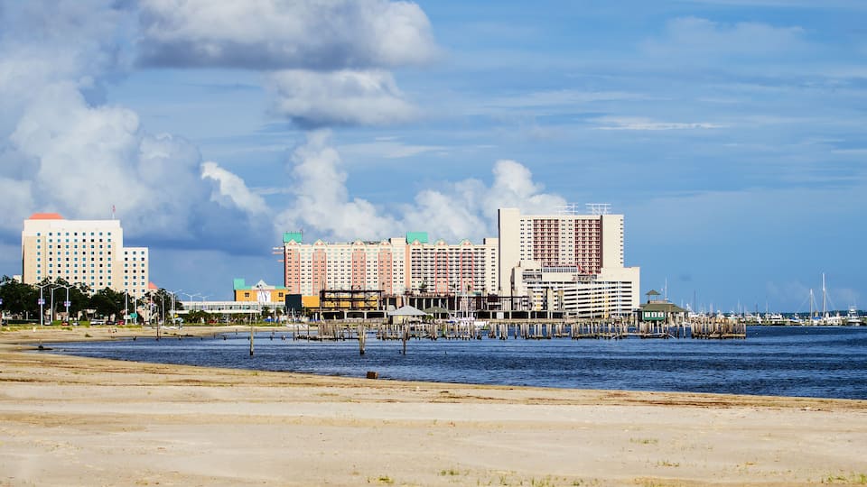 A coastal cityscape with a sandy beach, a marina, and several high-rise buildings.