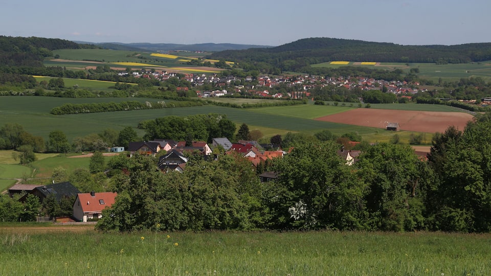 A rural landscape with fields, houses, and a small town nestled in the valley.