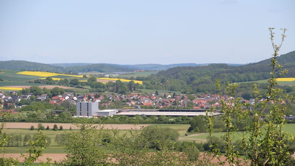 A rural landscape with a town, fields, and rolling hills.