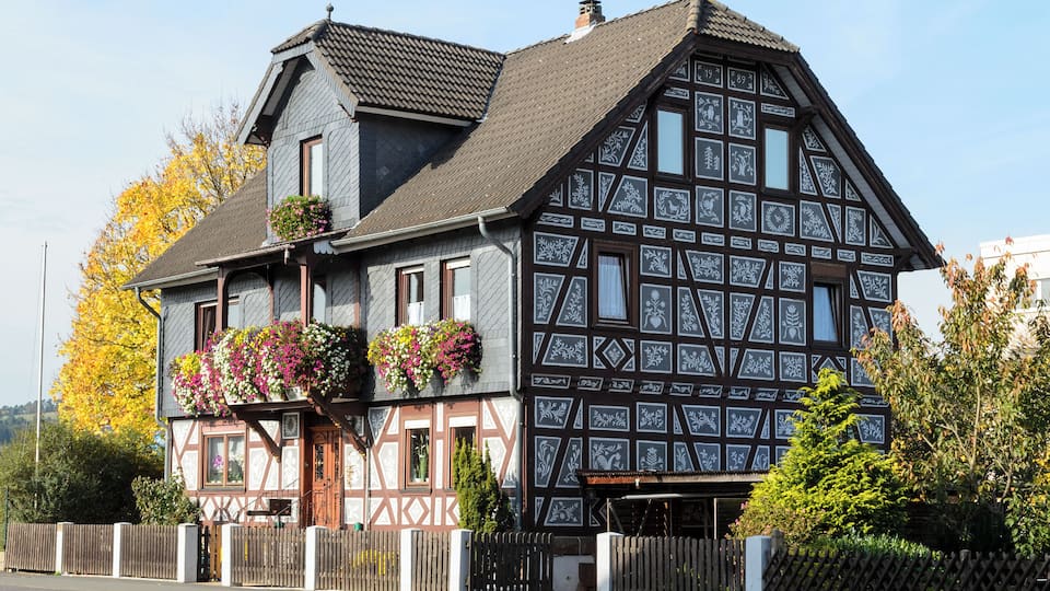 A traditional half-timbered house with flower boxes and a wooden fence.