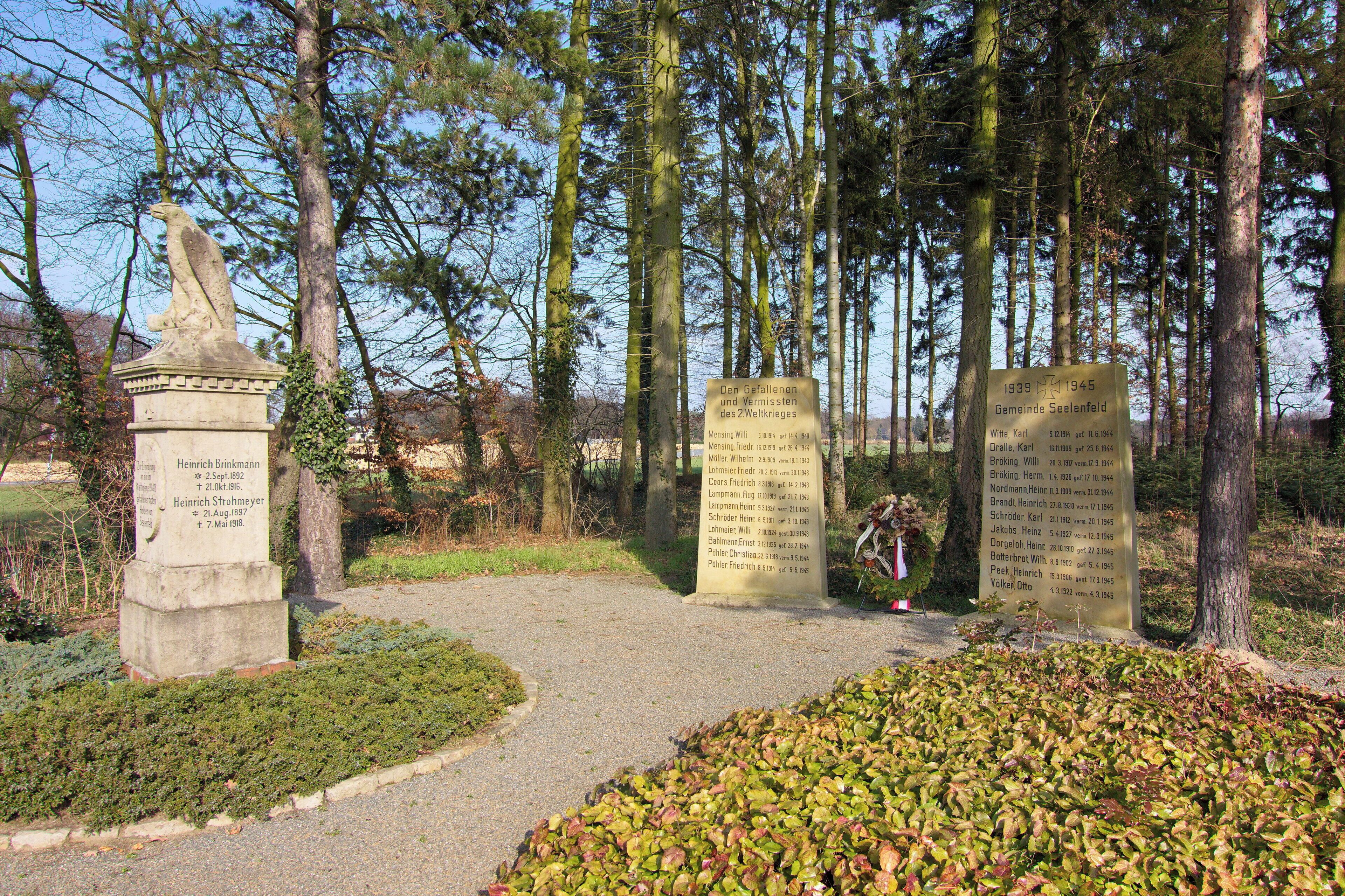 A memorial site with stone monuments and a path surrounded by trees.