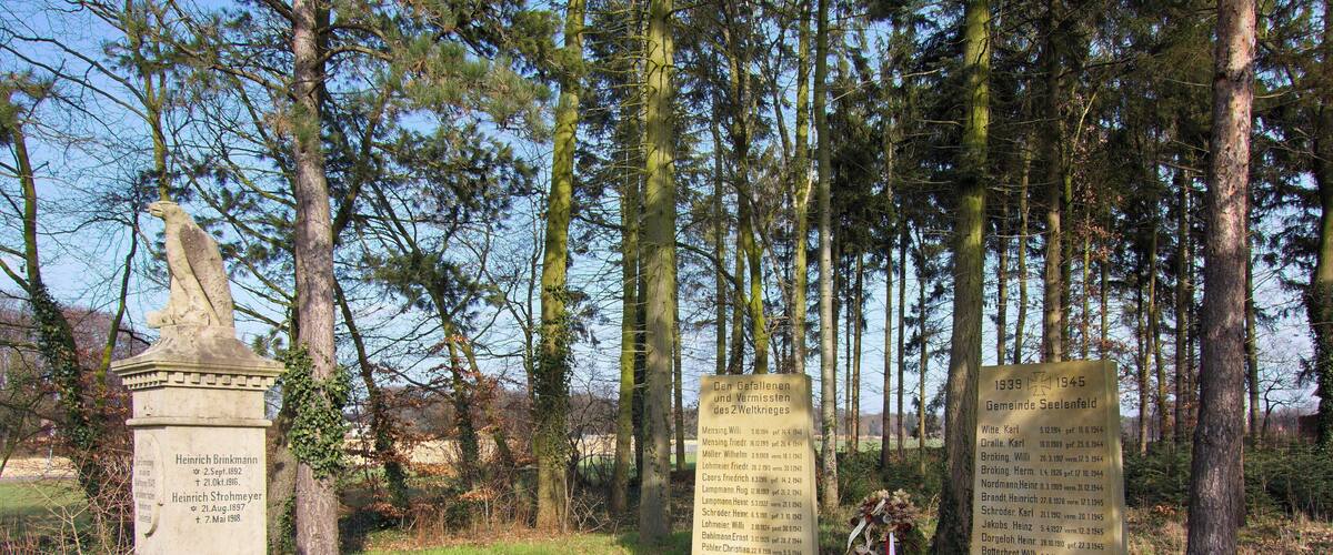 A memorial site with stone monuments and a path surrounded by trees.