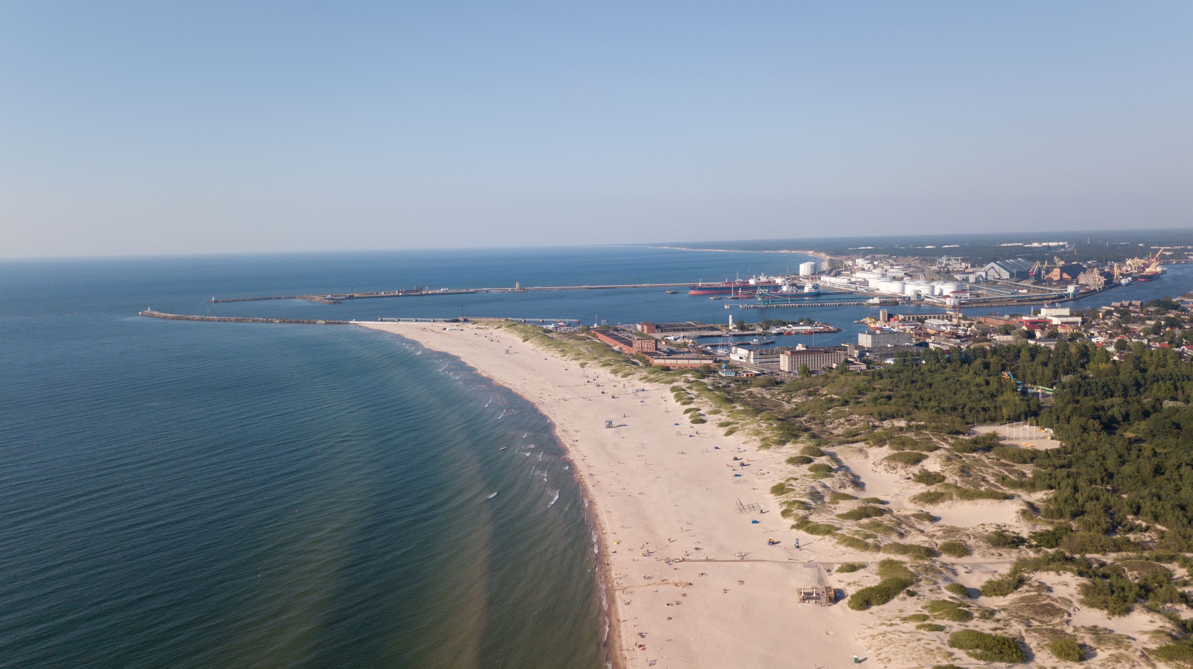 A coastal city with a beach, industrial facilities, and a bridge connecting to an island.