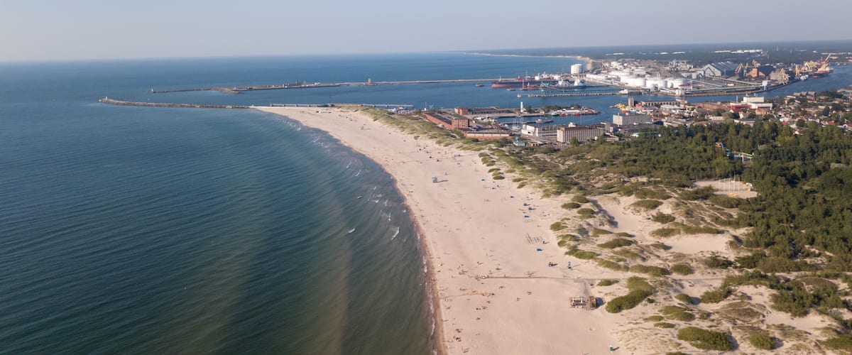 A coastal city with a beach, industrial facilities, and a bridge connecting to an island.