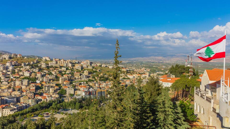 A cityscape with a prominent flag, dense residential buildings, and a clear sky.