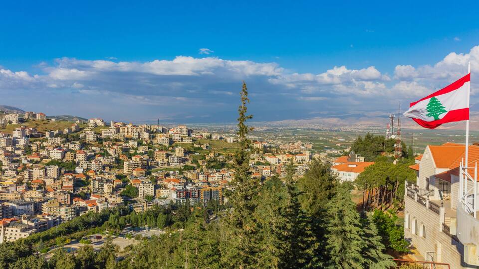 A cityscape with a prominent flag, dense residential buildings, and a clear blue sky.