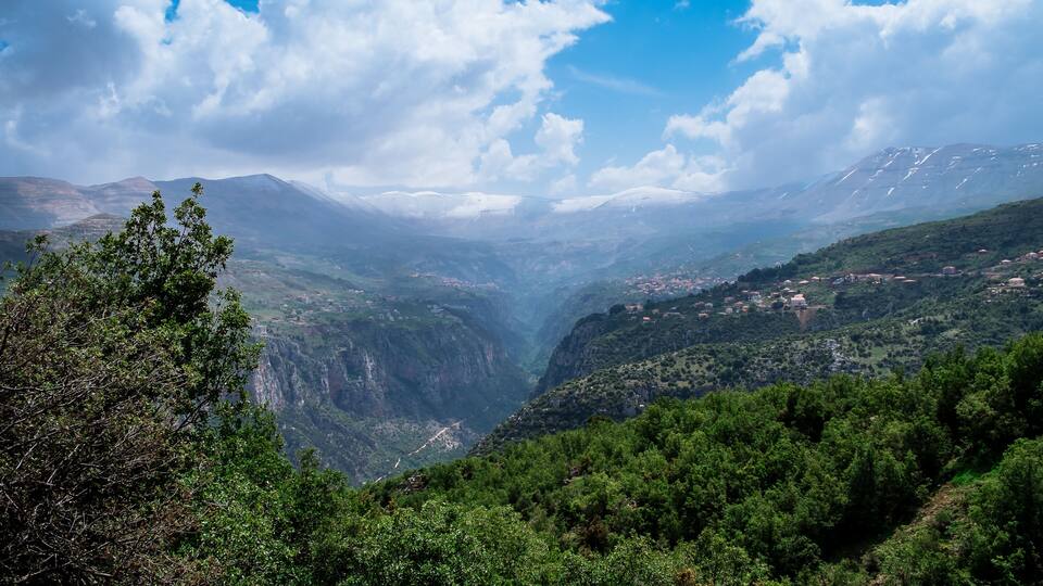 A valley with a river, mountains, and scattered houses.