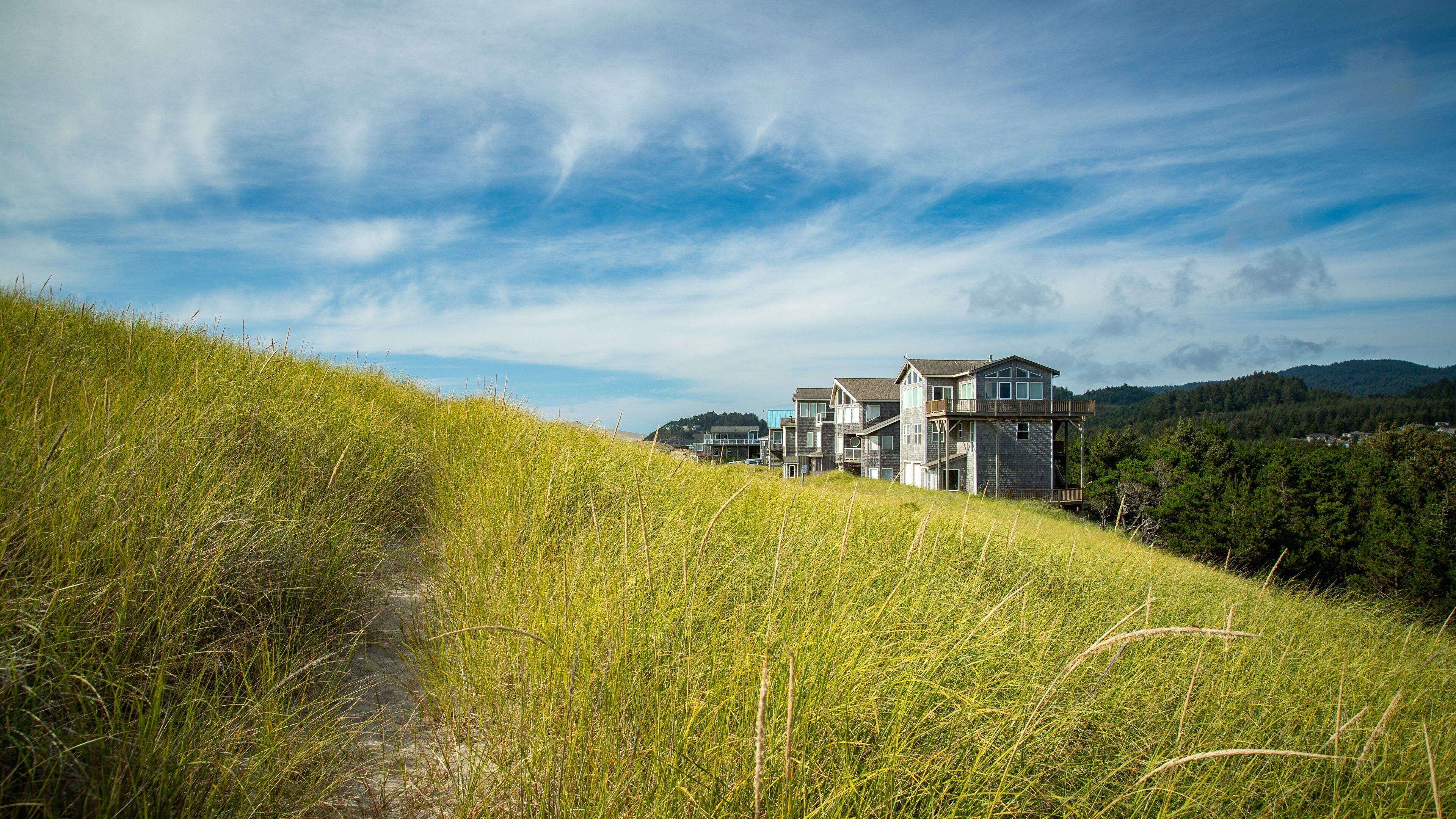 A modern house on a grassy hill with a clear sky.