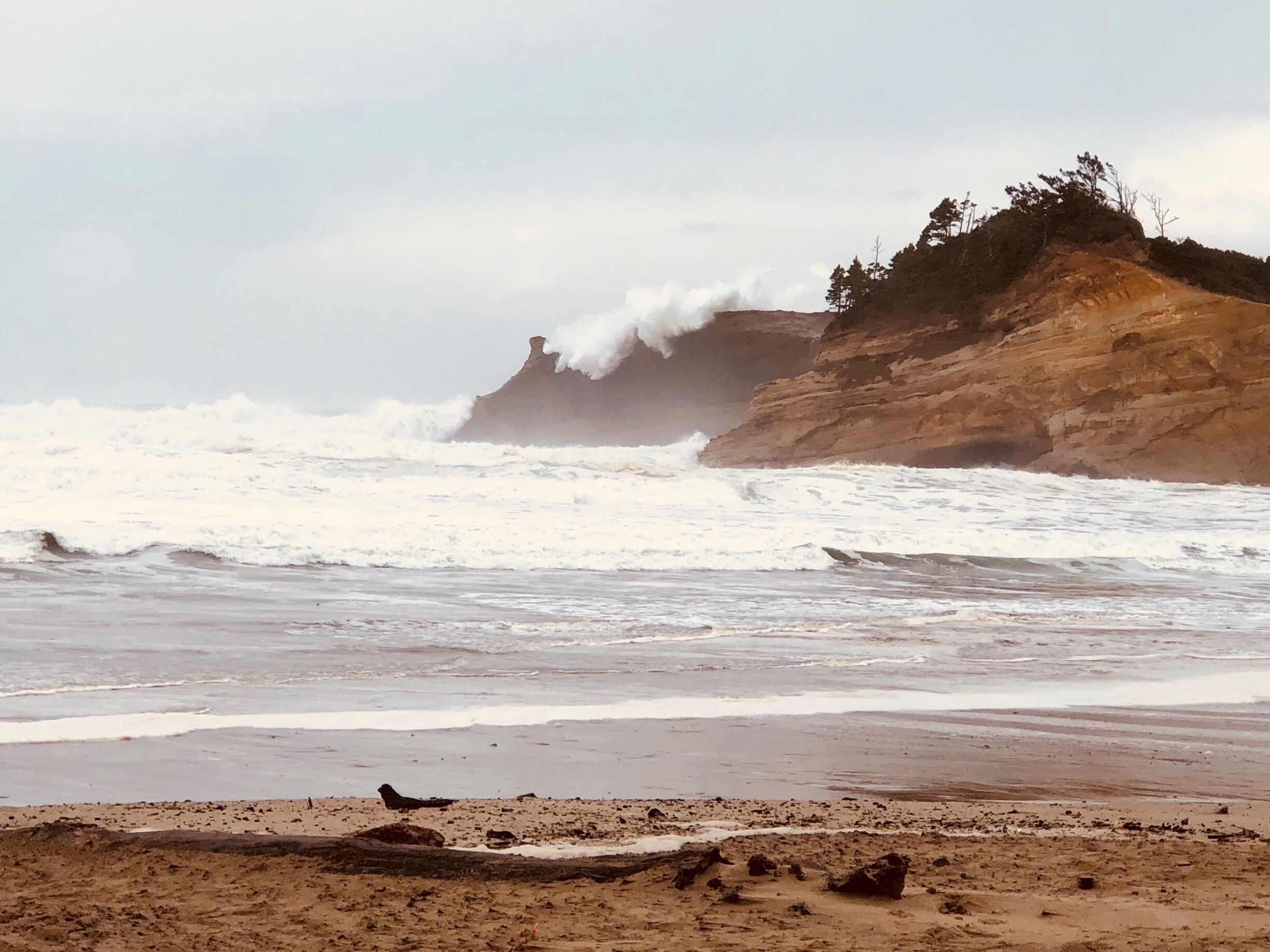 A beach with waves crashing against a rocky cliff.