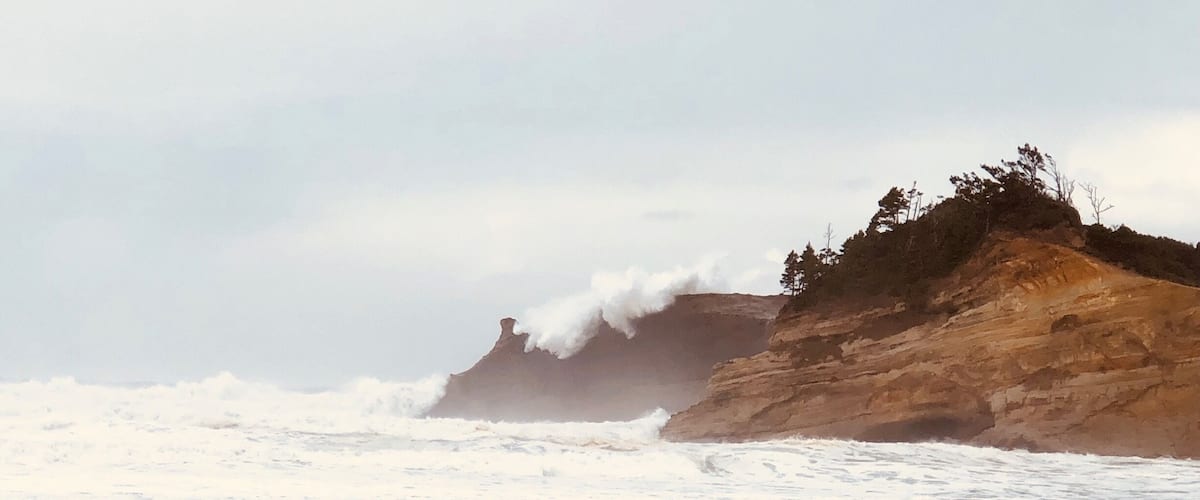 A beach with waves crashing against a rocky cliff.