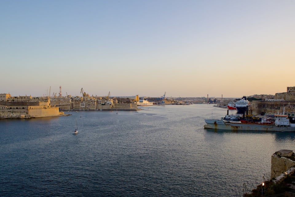 Un port avec des navires, un grand bâtiment et une vue sur la ville en arrière-plan.