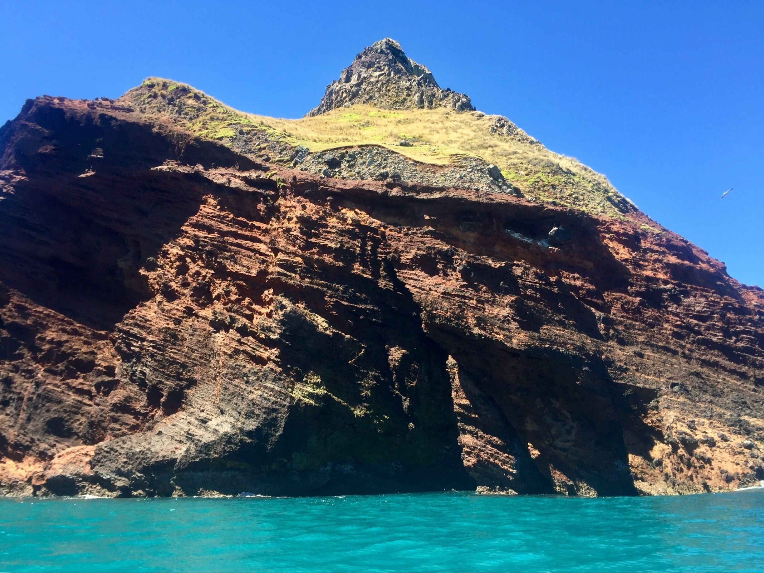 A rocky coastal landscape with a prominent cliff and turquoise waters.