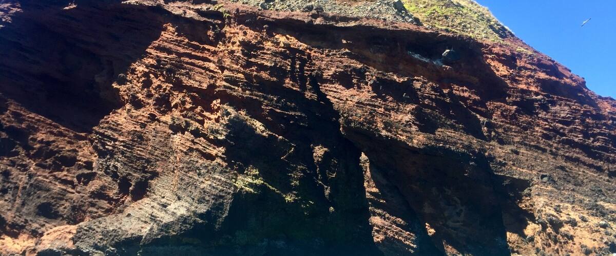 A rocky coastal landscape with a prominent cliff and turquoise waters.