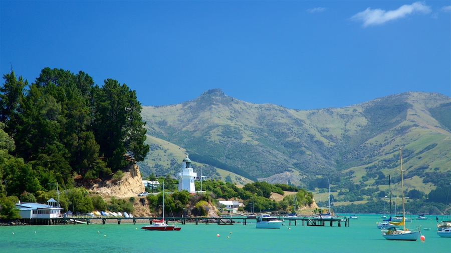 A coastal town with a lighthouse, boats, and mountains in the background.