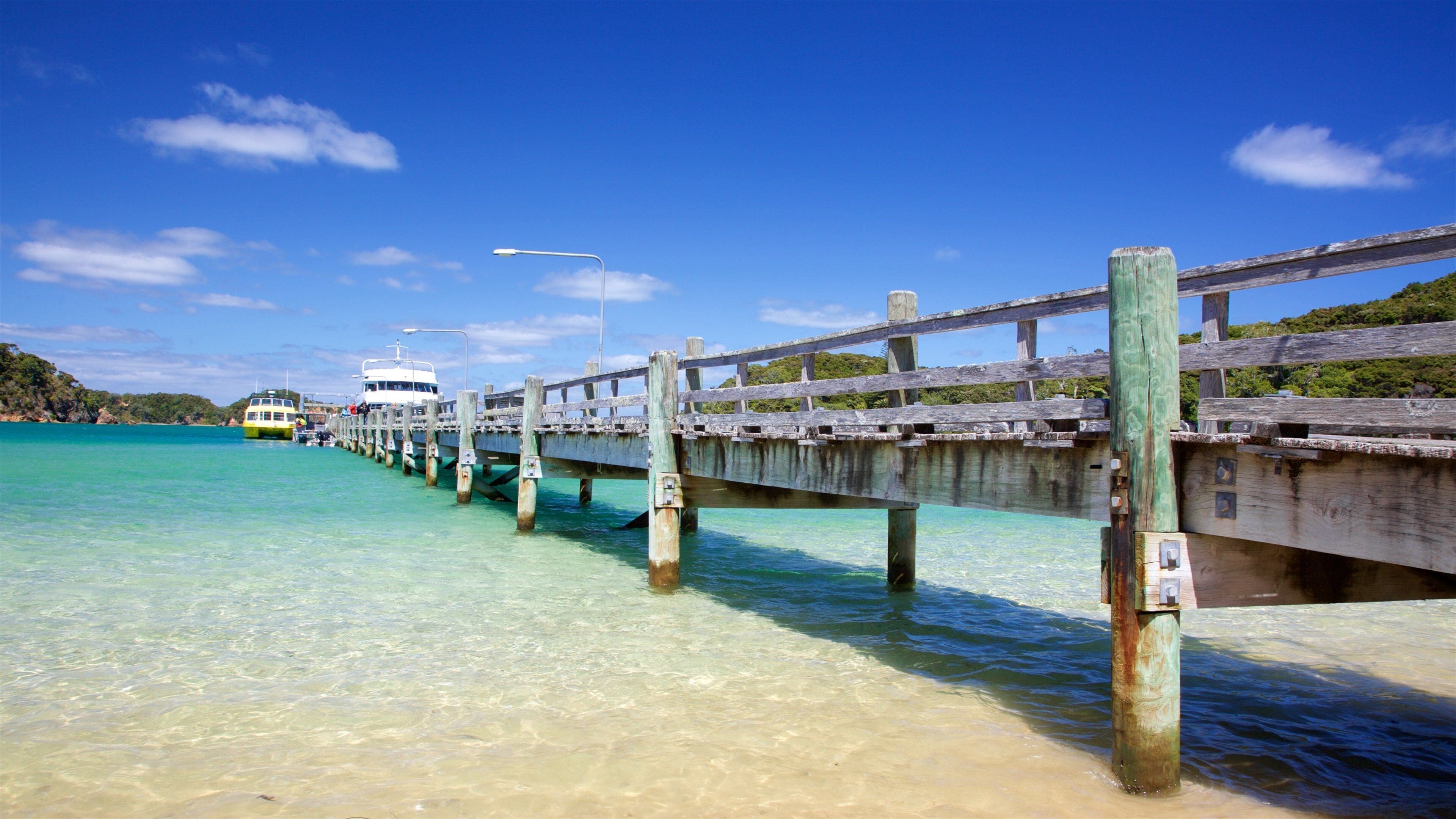 A wooden pier extending into turquoise waters with a boat docked at the end.