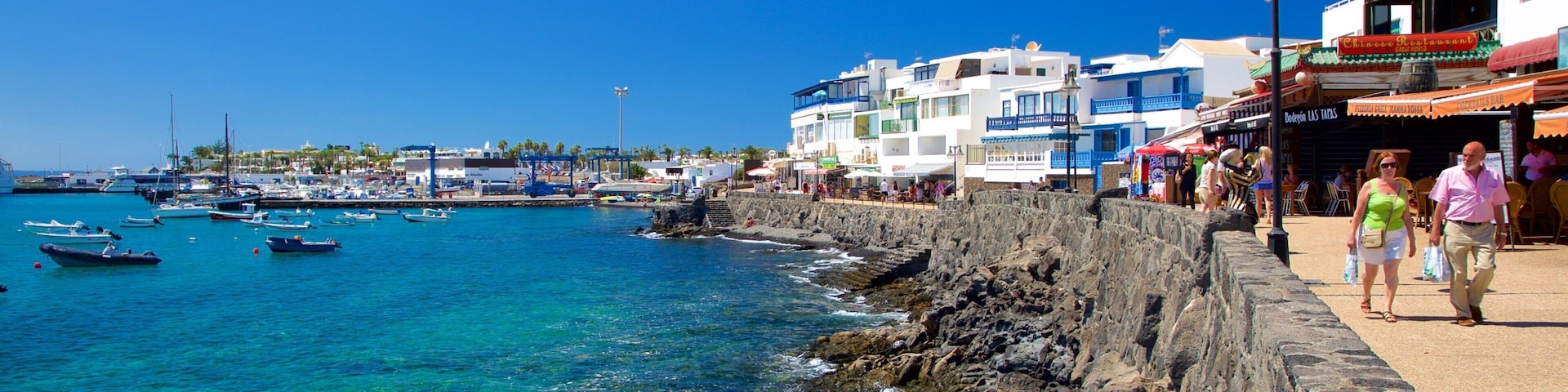 Playa Blanca showing rugged coastline, boating and a coastal town