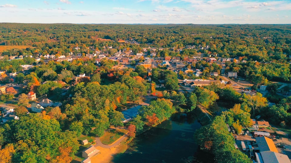 A river winding through a densely populated town surrounded by forested hills.