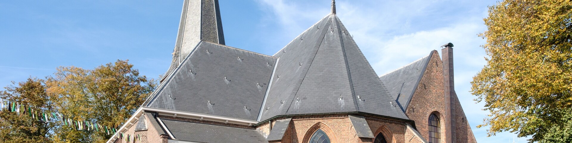 Una iglesia con un campanario alto y fachada de ladrillo.