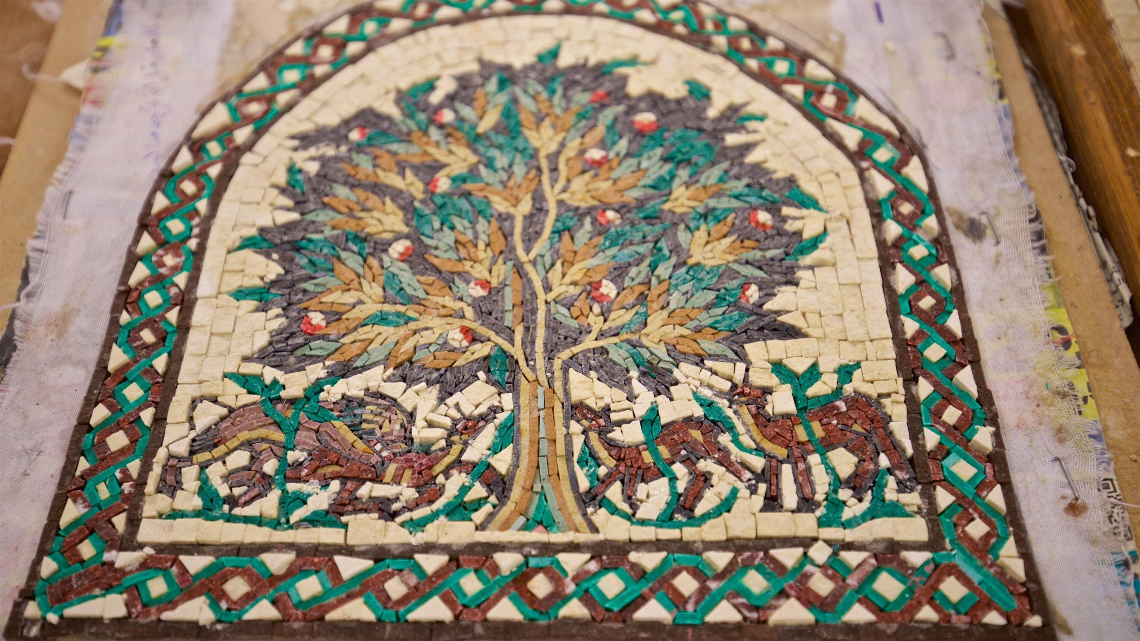 A detailed mosaic of a tree with animals and geometric patterns.