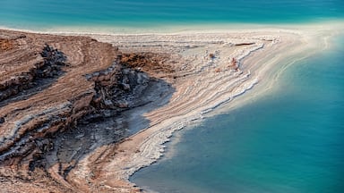 A coastal landscape with layered rock formations and a clear blue sea.