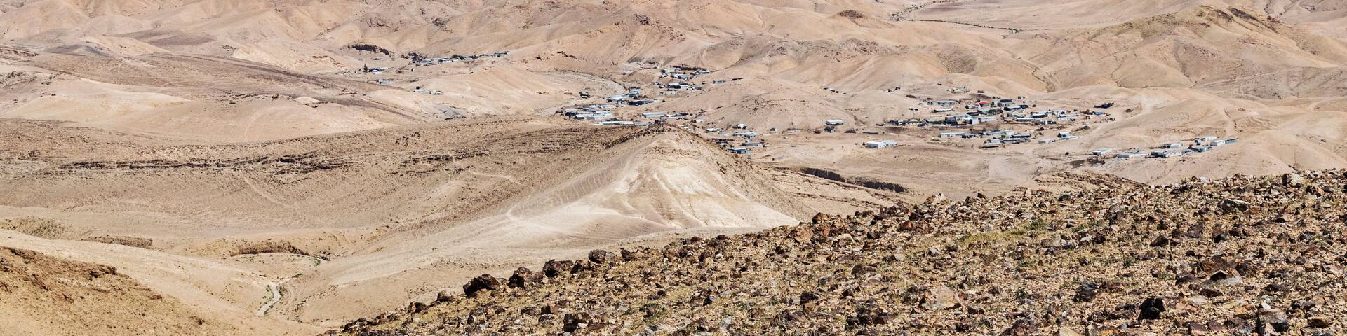 a group of bedouin villages can be seen in the hills between Arad in Israel and the Dead Sea with the Moab mountains of jordan in the background