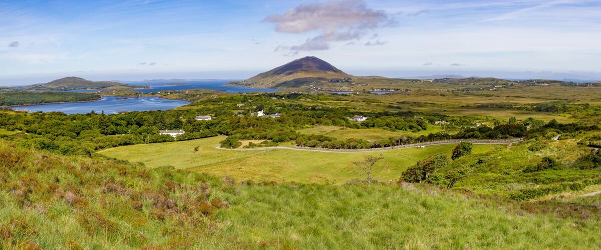 A coastal landscape with a prominent hill, a lake, and scattered houses.