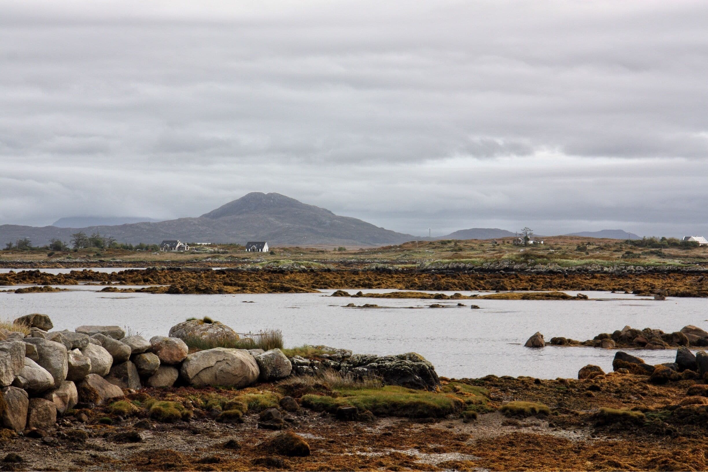 A coastal landscape with rocky shores, a small body of water, and distant white houses.