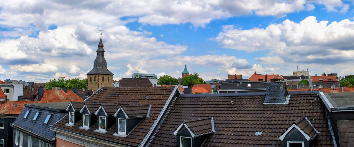 A cityscape with traditional buildings, a church spire, and a clear sky.
