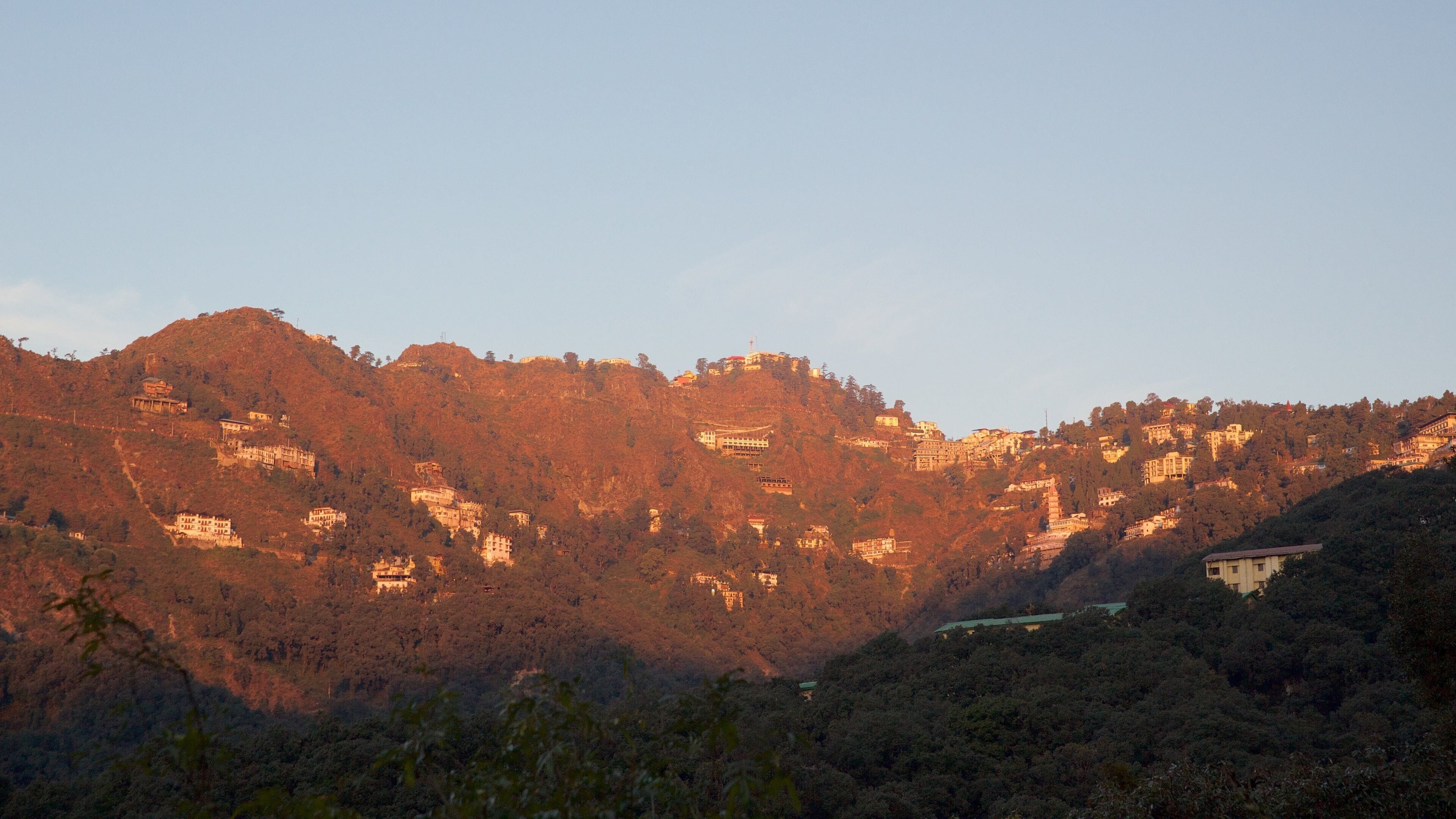 A mountainous landscape with scattered buildings and dense forest.