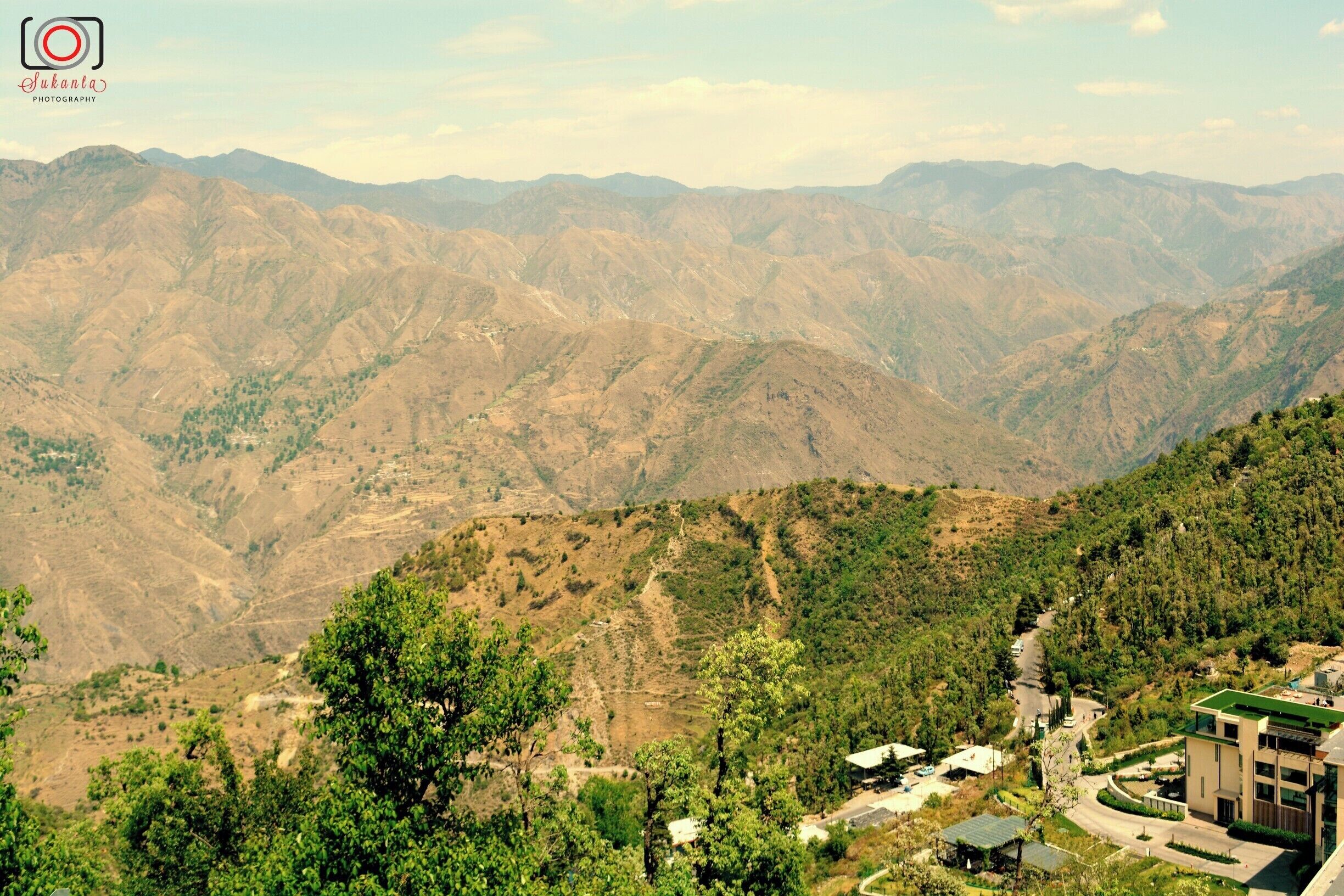 Gun Hill is a hilltop and lookout deck that commands unparalleled views over Mussoorie, the Doon Valley and the Garhwal Himalayas. Here, sample traditional Indian snacks, enjoy family-friendly fun at a small fairground and take a souvenir photo while dressed in traditional clothing. Gun Hill sits at a height of 6,640 feet (2,020 meters) and is the second-highest point in Mussoorie.
Reach the viewpoint by riding on the cable car, which travels up for about 1,300 feet (400 meters) from The Mall. Watch as Mussoorie’s rooftops disappear into the distance and marvel as the views of the surrounding countryside become clearer. An alternative way to get here is to walk along a winding trail that leads off from The Mall. The walk takes about 30 minutes.
At the summit of the hill are views of the rolling green hills of the Doon Valley in all directions. On a clear day you can spot the snow-capped peaks of the Garhwal Himalayan range. These include the towering Bandarpunch and Gangotri glacier. Pay a small amount to use binoculars to observe the landscapes in closer detail.  
Both local residents and tourists enjoy visiting Gun Hill. Kids will have fun playing on the roundabouts, ring throwing and balloon shooting games, among other attractions. Professional photographers offer visitors the chance to dress in typical Indian clothing and pose for a souvenir photo. Warm up on a chilly day with a cup of masala chai tea from one of several cafés and restaurants. Sample Indian snacks including chana kulcha, which is spicy chickpeas served with flatbread.
The hilltop is above Mussoorie’s town center. Combine your visit with a stroll on The Mall, a lively commercial promenade. Alternatively, hike or ride on horseback along Camel’s Back Road, a scenic trail named after a rocky formation that resembles a camel.
Gun Hill is accessible daily. The cable car runs every day. Purchase a roundtrip ticket for the cable car which is cheaper than purchasing two separate single tickets.