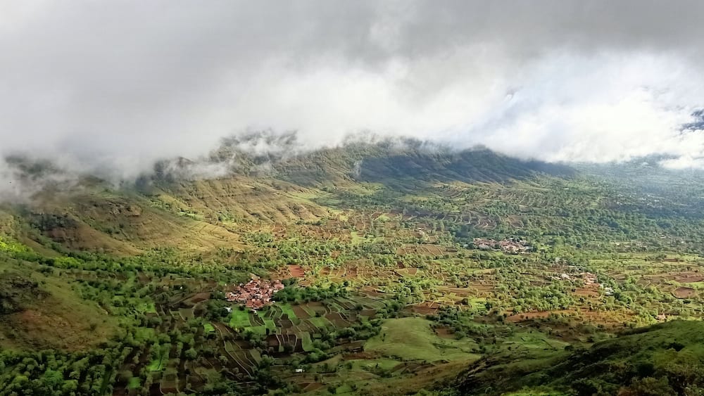 A mountainous landscape with terraced fields and a small village.
