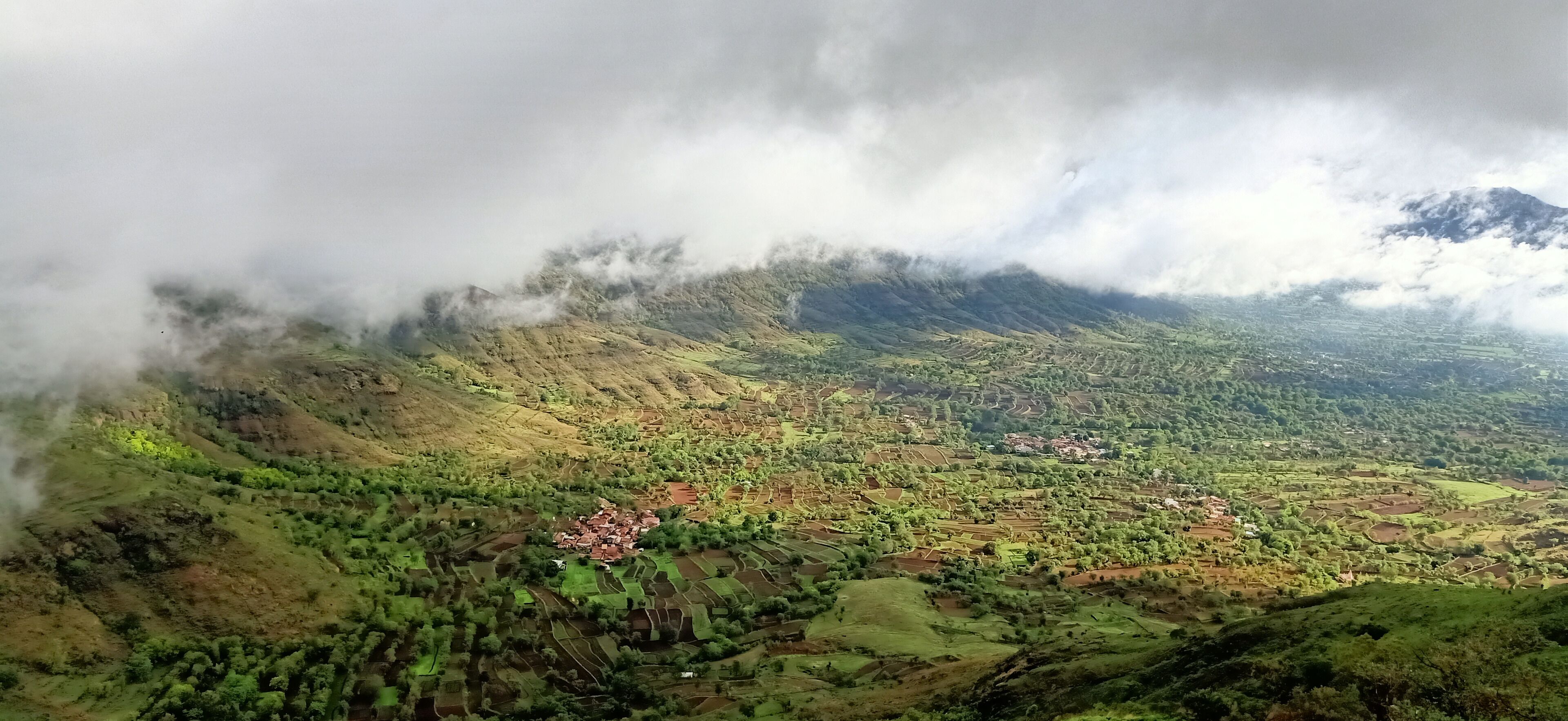 A mountainous landscape with terraced fields and a small village.